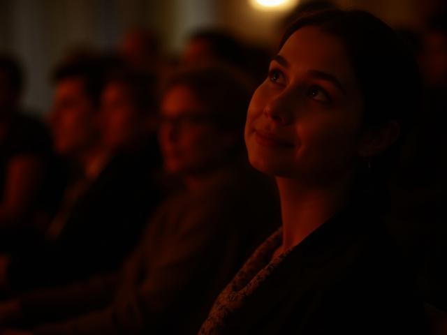 Audiencia capturada por un recital de poesía en Café Lumina, con iluminación tenue y ambiente concentrado.
